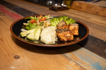 A delicious plate of Salmon and salad on a wooden kitchen work top