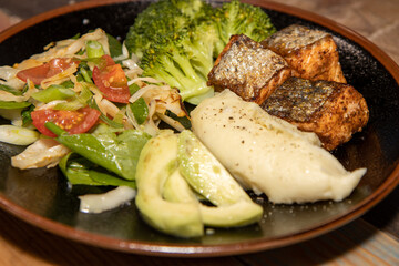 A delicious plate of Salmon and salad on a wooden kitchen work top