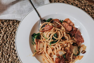 Spaghetti bacon, garlic, basil, dried chili pepper on fork on wood table. Parsley in dish,Spaghetti pasta with copy space,Italian food,