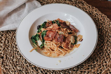Spaghetti bacon, garlic, basil, dried chili pepper and cherry tomato on wood background. Top view. Copy space