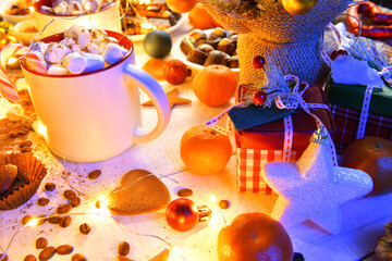 sweet food and decoration background for merry christmas or new year holiday with night illumination - chocolate candies, tangerines, cookies, marshmallow and cocoa latte on white wood