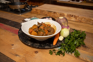 A delicious plate of Venison Stew with root vegetables on a wooden kitchen work top