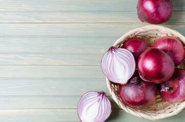 Red onions in a wicker basket. Fresh harvest. Light wood background