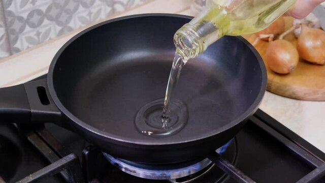 Pouring oil on frying pan. Cooking process. Chef pours sunflower oil into frying pan