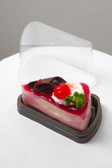 a piece of strawberry jelly cheesecake in the take away plastic box - 402524498