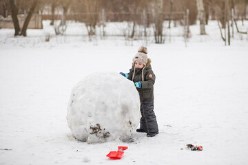 Boy playing with snow and having fun in winter