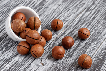 Macadamia nuts in small white bowl on black wooden table.