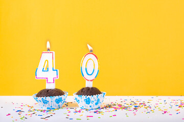 40 number candle on a cup cake with colorful sprinkles and yellow background fortieth birthday...