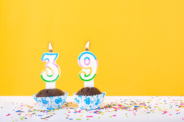 39 number candle on a cup cake with colorful sprinkles and yellow background thirty ninth birthday...