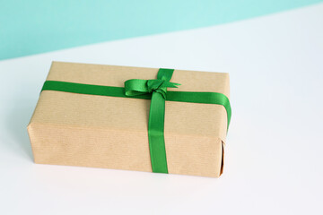 Christmas gift box wrapped on brown kraft paper with green ribbon. Sustainable living concept. Minimalism decoration.