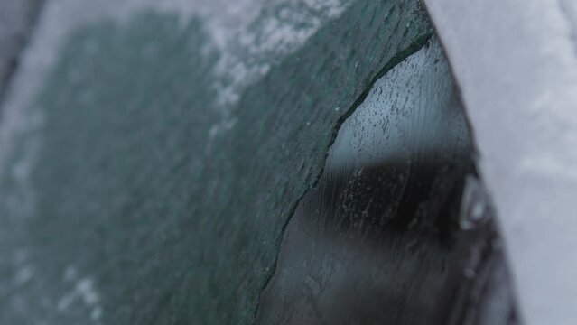 Aged bearded man cleans electric automobile roof with black and yellow snow brush on winter day