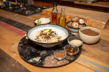 A bowl of spicy noodles surrounded by the ingredients used to make the dish