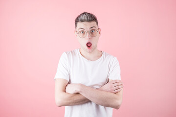 Surprised man in eyeglasses wearing white undershirt over pink background