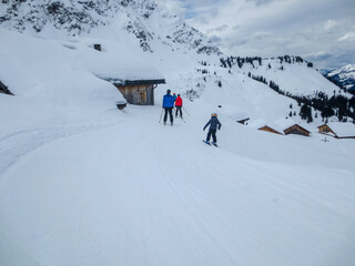 Skifahrer auf einer Piste vor einem einsamen Bergdorf