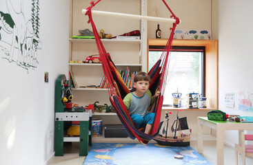 Ein Junge sitzt gelangweilt in seinem Kinderzimmer