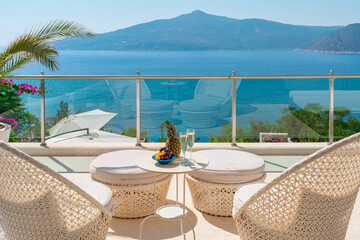 Fototapeta na wymiar Romantic summer vacation view. Luxury travel balcony with ocean view. Drinks and fruits on table holiday destination.