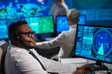 Workplace of the air traffic controllers in the control tower. Diverse team of aircraft control officers works using radar, computer navigation and digital maps. Aviation concept.