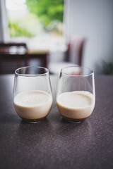 couple of espresso martinis in wine glasses on kitchen counter with dining room bokeh