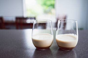 couple of espresso martinis in wine glasses on kitchen counter with dining room bokeh