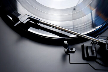 Black vinyl record spinning on a turntable - close up of a tonearm , lp and turn table