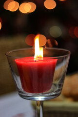 red candle flame at night with lights in background