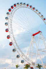 Ferris wheel with blue sky. White metal construction of an attraction Ferris wheel with observation cabs at amusement park