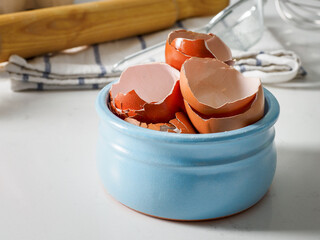 Egg shell on white table. Egg shells in a ceramic bowl. Eggshell close-up.