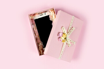 Open beautiful gift box with smart phone inside isolated on pastel pink background. Flat lay, copy space.