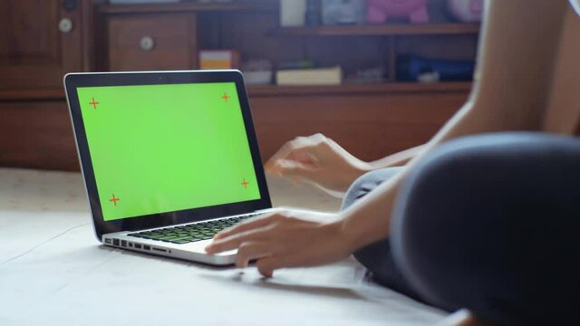Young woman using with chroma key green screen laptop on bedroom for digital workout sessions at home.