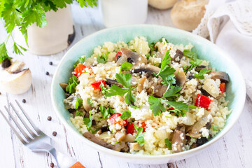 Healthy diet food. Vegan salad close-up with couscous and champignons on a wooden kitchen table.
