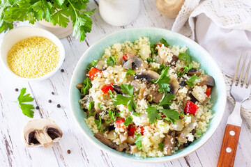 Healthy diet food. Vegan salad with couscous and champignons on a wooden kitchen table.