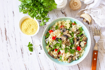 Healthy diet food. Vegan salad with couscous and champignons on a wooden kitchen table. Top view flat lay. Copy space.