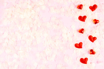 Valentine's Day, wedding, love concept. Celebration pink background with red satin hearts and paper pink confetti. Top view, flat lay, copy space.