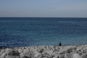 Girl sitting on the rocks and looking to the sea 