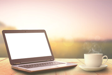 Fototapeta premium laptop and a cup of coffee on wooden table and sunrise nature background