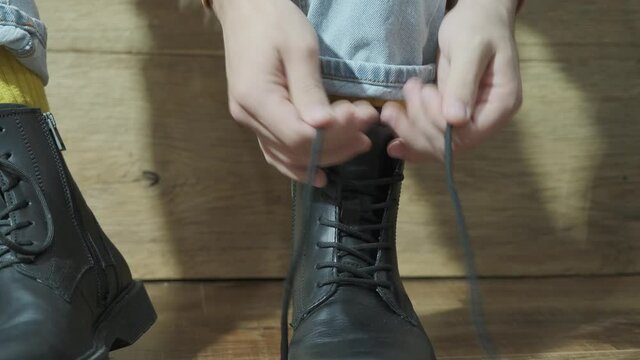 Man puts on and laces up black winter boots