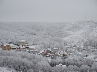 above view of snow-covered city and urban houses on horizon in overcast winter day