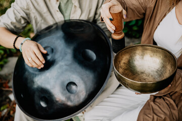 close up photo of handpan in a duet with Tibetan bowls in the hands of masters