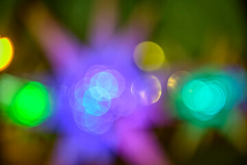 Multicolored holiday lights in defocus. Blurred abstract illuminate decorative lights with bokeh in night background.