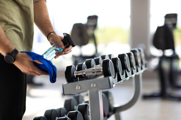 Fitness staff cleaning exercise machines alcohol sanitizer spray at the gym. preventive disease of...