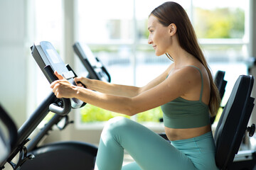 Fototapeta na wymiar Healthy Lifestyle and Sport Concepts. Attractive young woman training on bike at the gym.