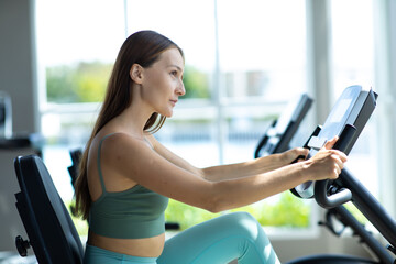 Healthy Lifestyle and Sport Concepts. Attractive young woman training on bike at the gym.