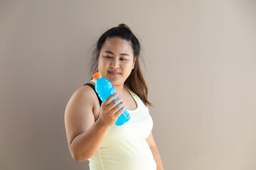 Portrait of Overweight Asian woman in sportswear holding bottle of water and checking performance or heart rate pulse trace.