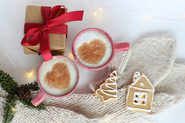 two mugs with frothy cappuccino and hearts on the festive table top view. warming home-like atmosphere on the day of lovers