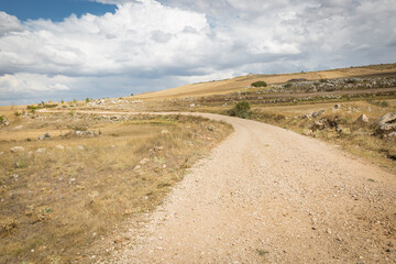 a gravel road on a summer landscape next to Hontanas, province of Burgos, Castile and Leon, Spain