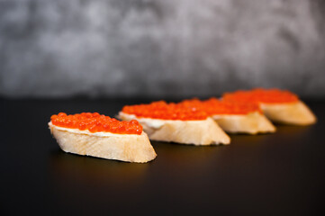 Sandwiches with salmon red caviar on a cement background