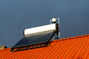 Side view, solar water heater boiler on rooftop, dramatic dark sky in the background.