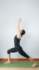 Asian young woman wear a black yoga outfit . Practicing yoga Standing Asanas Action A&B VIRABHADRASANA A&B (warrior I,II). Home yoga practice on white background