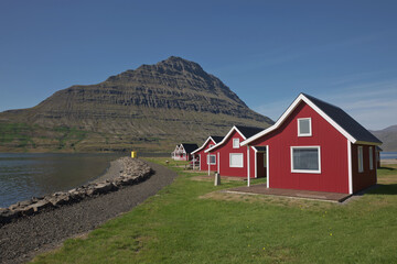 Traditional red painted wooden panel house with mighty Holmatindur mountain in the background in Eskifjordur, East Iceland