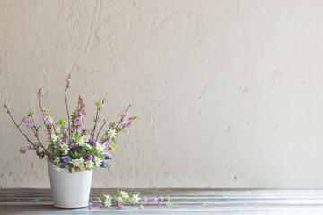 spring flowers in white bucket on background  old white wall
